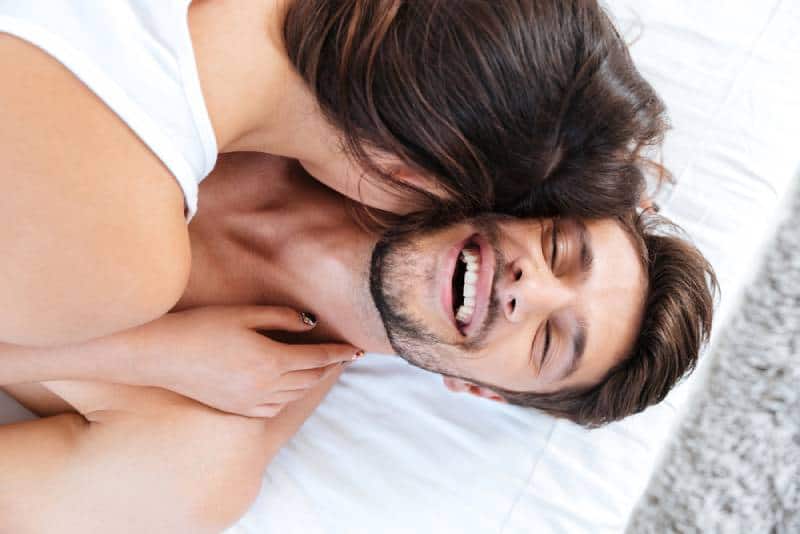 Nahaufnahmeporträt eines jungen lachenden Paares im Bett zu Hause