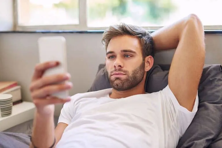 Ein junger Mann, der auf der Couch liegt und im Internet surft