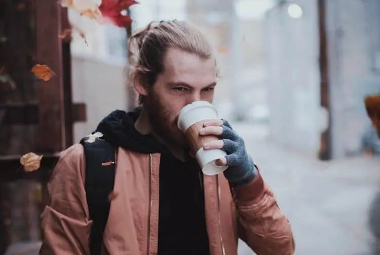 Ein Mann geht die Straße entlang und trinkt Kaffee zum Mitnehmen