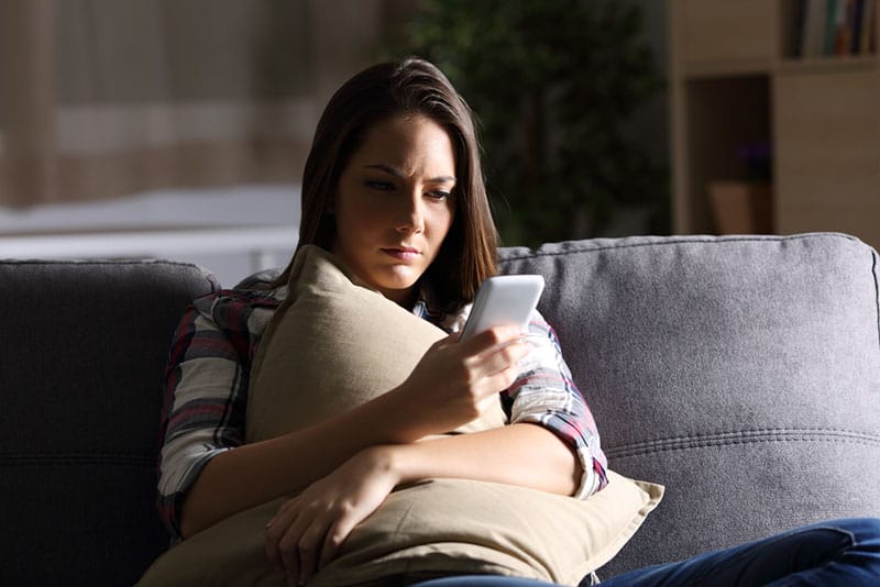 junge besorgte Frau, die Telefon ansieht