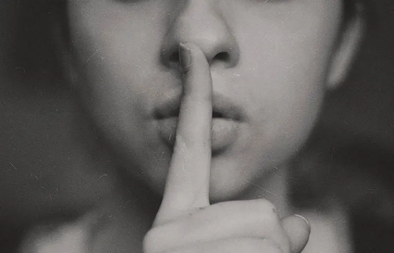 ein Mädchen hält einen Finger über die Lippen