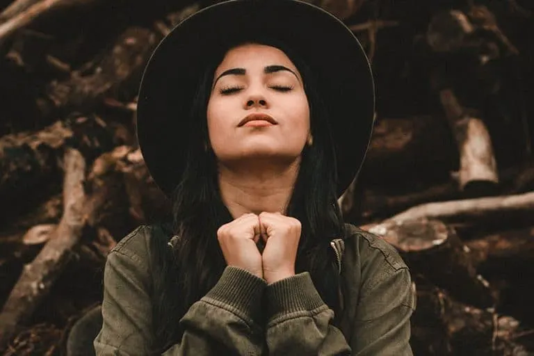 ein Mädchen mit Hut, das in der Natur betet