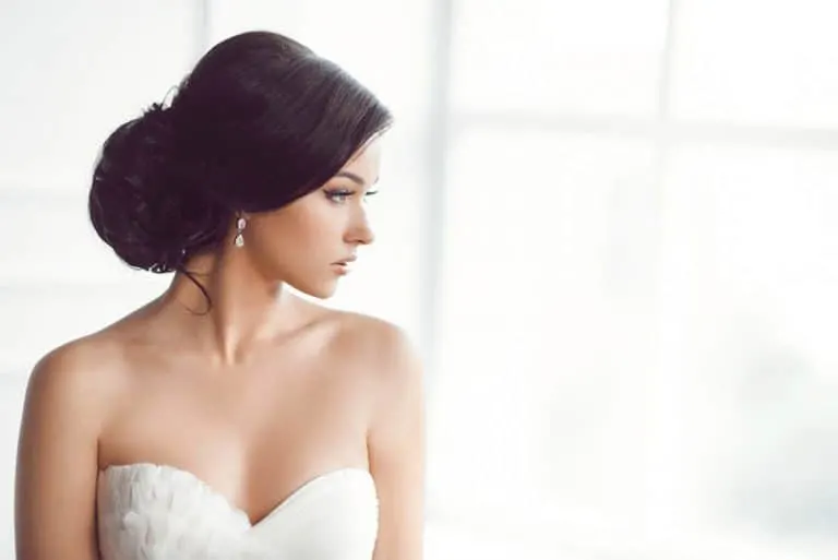 Ein Mädchen in einem weißen Hochzeitskleid steht am Fenster