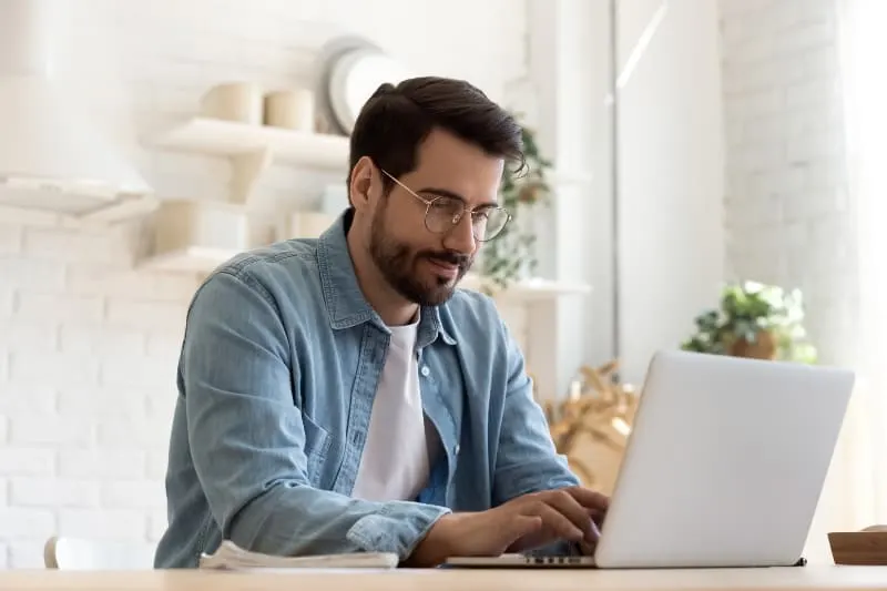 Ein Mann mit Bart benutzt einen Laptop