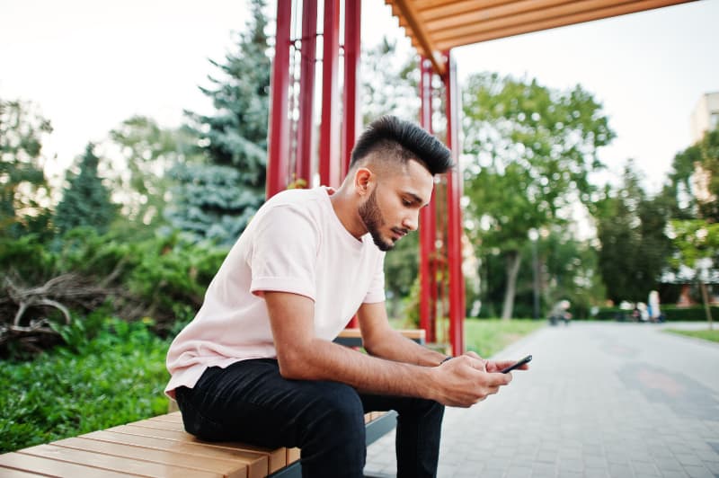 Ein Mann sitzt auf einer Bank und benutzt ein Handy