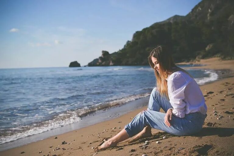 Traurige Frau sitzt am Strand