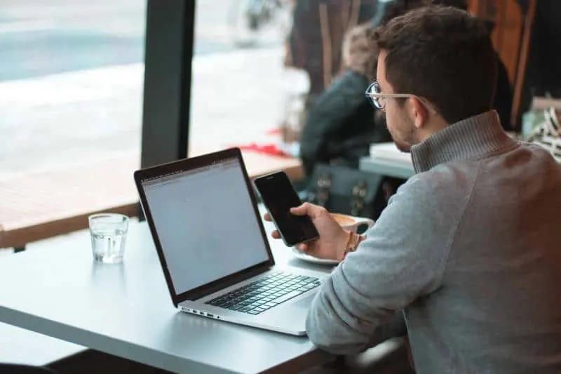 Mann, der nahe Tisch mit Laptop und Smartphone nahe Fenster sitzt