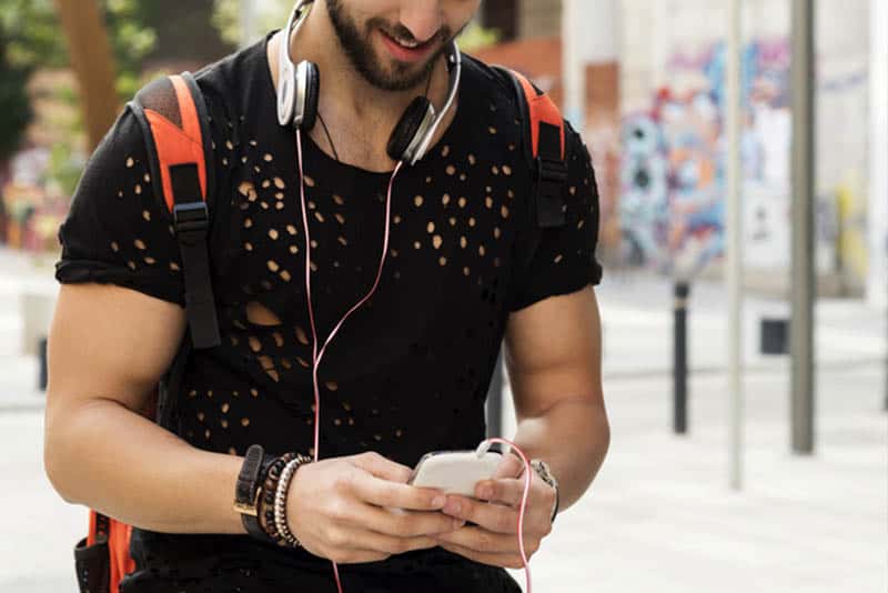 Mann im Kurzarmhemd, der draußen geht und Telefon benutzt