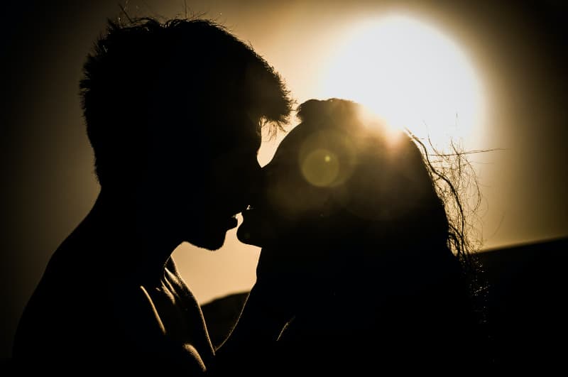 Mann und Frau küssen sich unter der Sonne