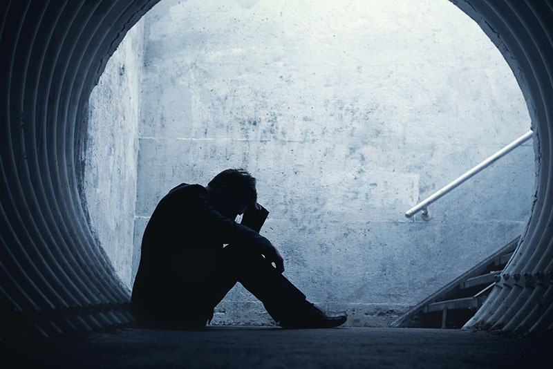 Seitenansicht des depressiven Mannes, der draußen sitzt