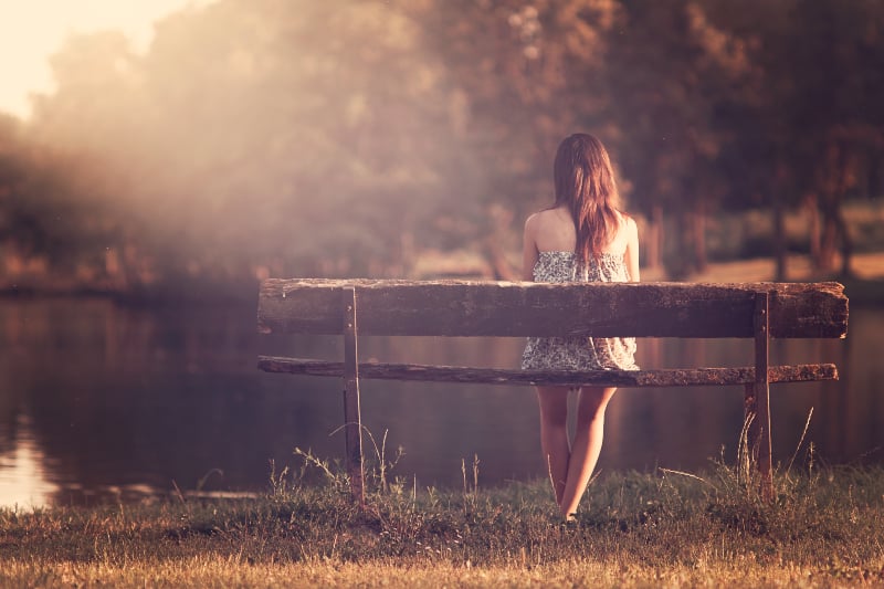ein einsames Mädchen sitzt auf einer Bank