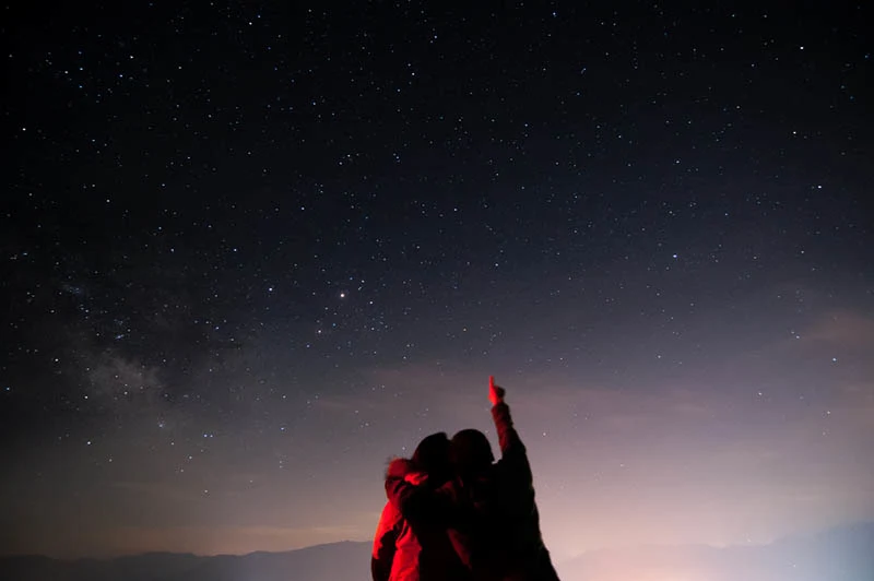 ein liebendes Paar in einer Umarmung, das die Sterne beobachtet