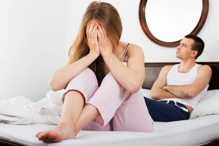 ein trauriges Mädchen, das auf dem Bett sitzt und weint