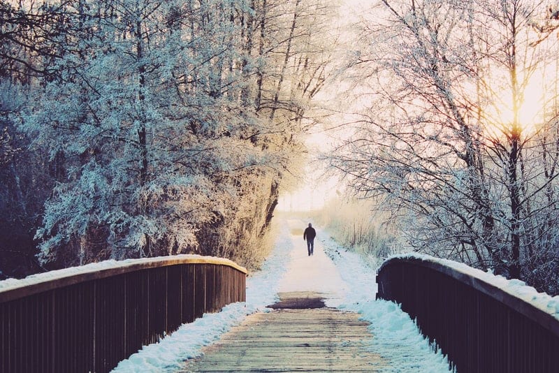 eine Holzbrücke und in der Ferne ein Mann, der geht