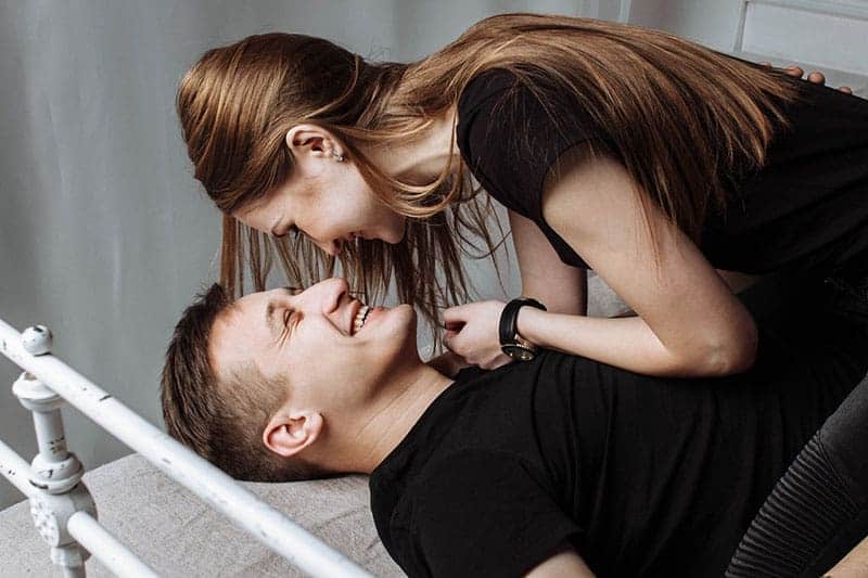 eine lächelnde Frau und ein Mann, die das Bett genießen