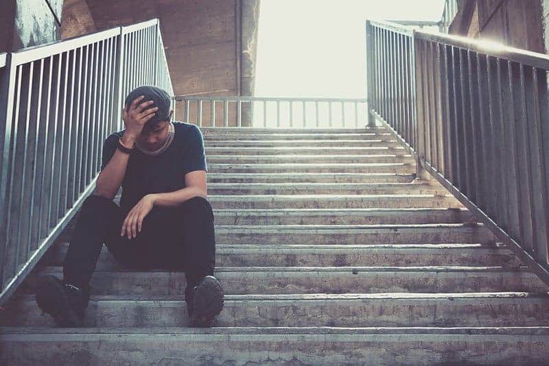 trauriger Mann, der draußen an der Treppe sitzt