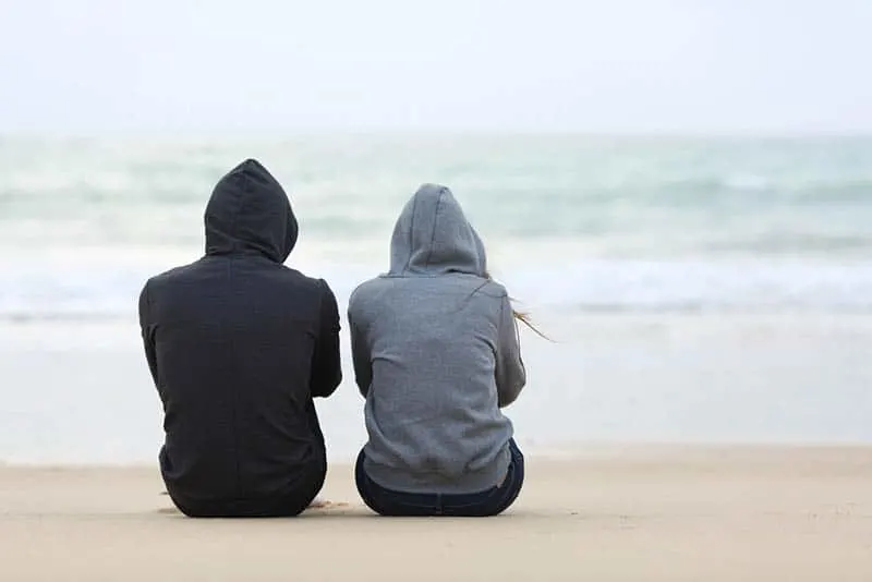 trauriges Paar, das am Strand sitzt
