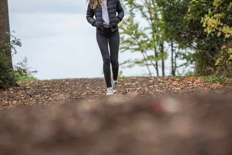 Frau, die schwarze Jeans und schwarze Jacke trägt, die draußen gehen