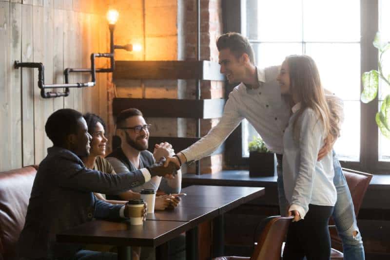 Freunde treffen sich im Café, junger Mann stellt sich vor