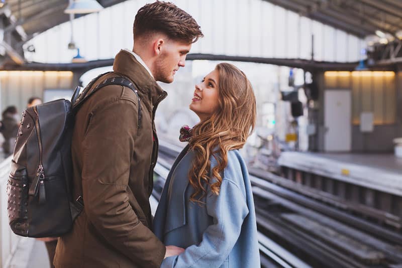 Paar hält ihre Hand und schaut sich am Bahnhof an