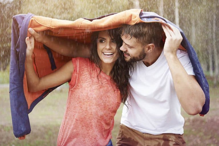 ein Paar versteckt sich unter einer Regenjacke