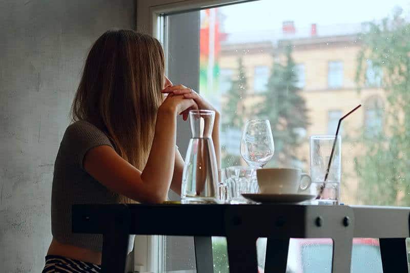 nachdenkliche Frau, die durch Fenster im Café schaut