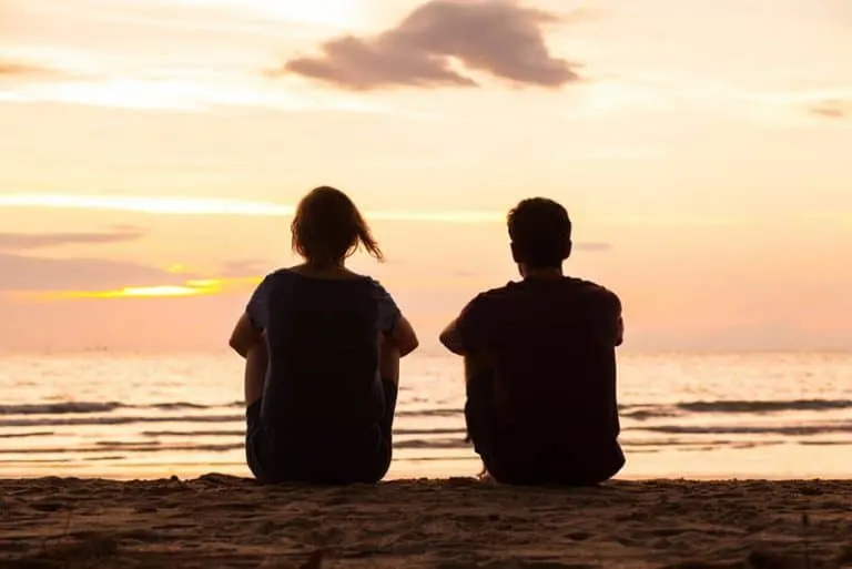 Ein Paar beobachtet den Sonnenuntergang am Strand