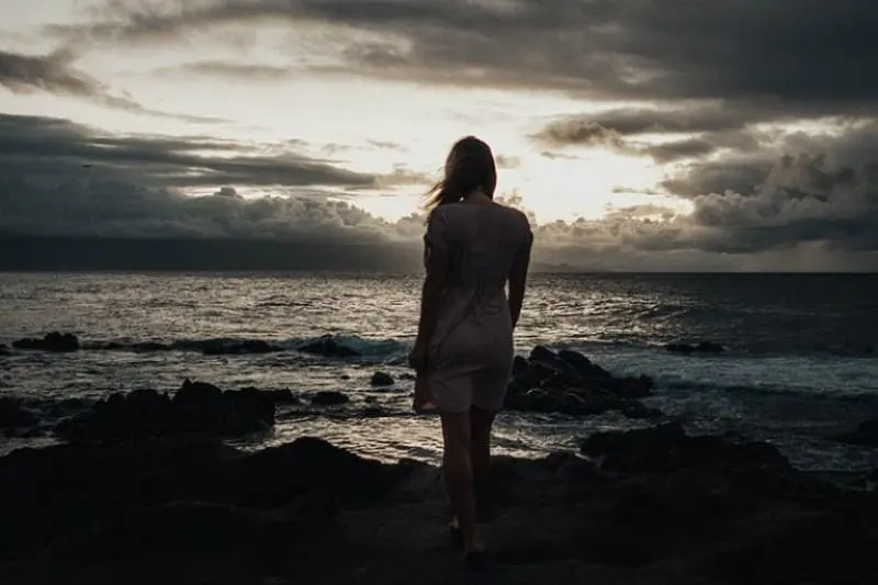 ein Mädchen, das auf einem Felsen am Meer steht