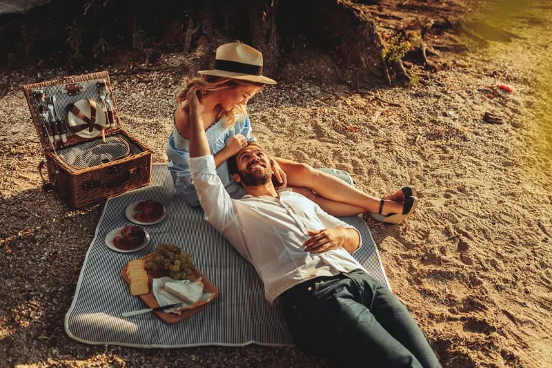 Beautiful couple enjoying picnic time on the sunset