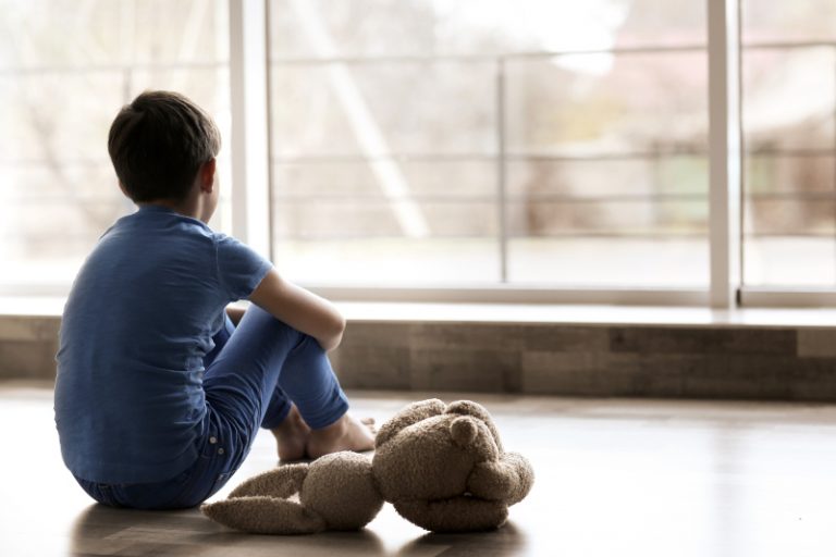 Ein kleiner trauriger Junge sitzt auf dem Boden