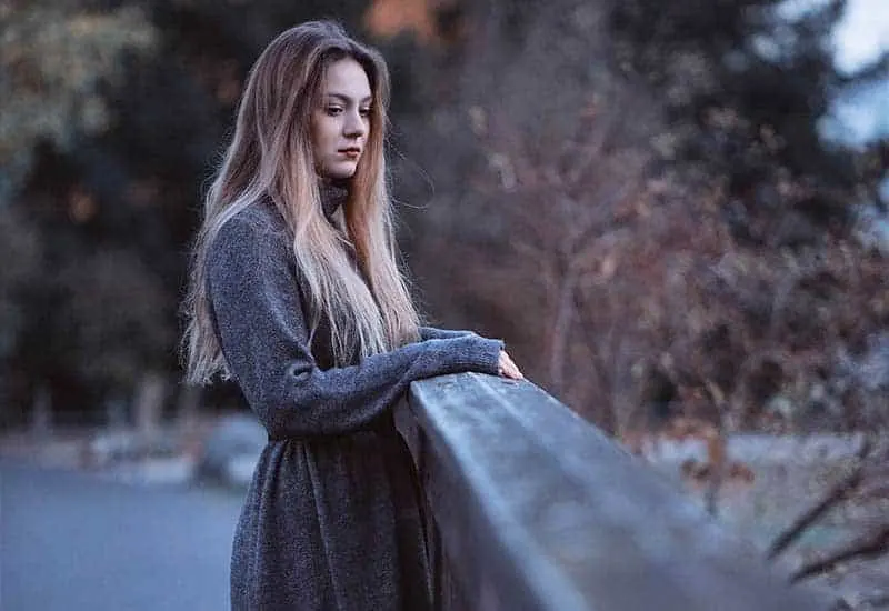 Auf der Brücke steht eine traurige Frau in einem grauen Mantel