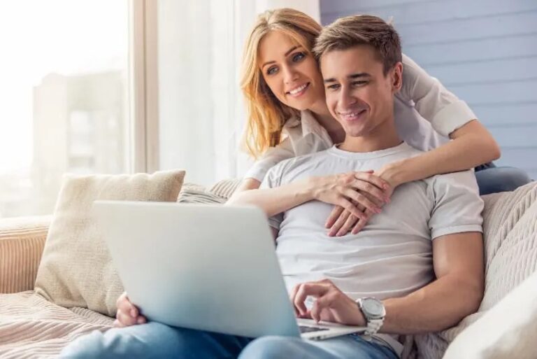 laechelndes Paar schaut auf Laptop