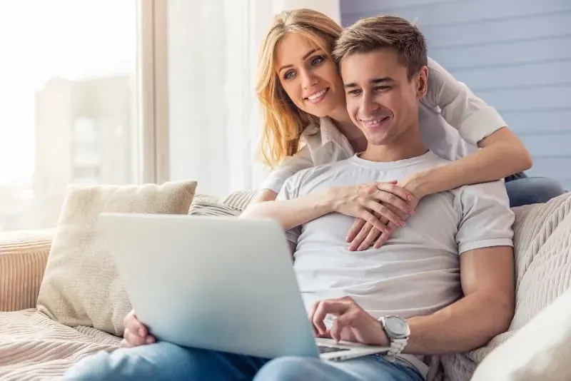 laechelndes Paar schaut auf Laptop