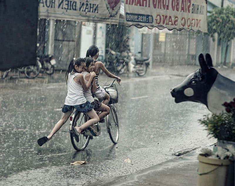 Drei junge Mädchen fahren im Regen Fahrrad