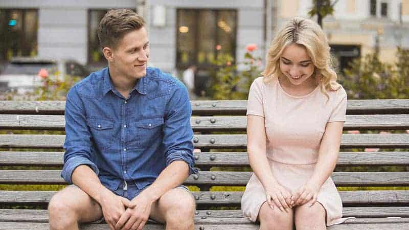 Ein Mann und ein Mädchen sitzen auf einer Holzbank und flirten
