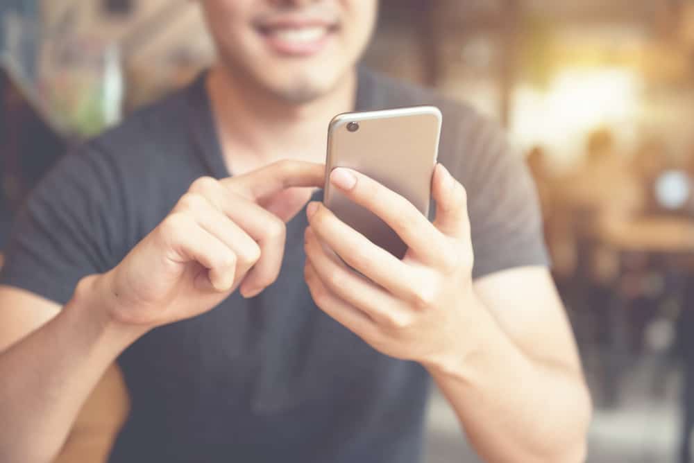 Ein lächelnder Mann benutzt ein Smartphone