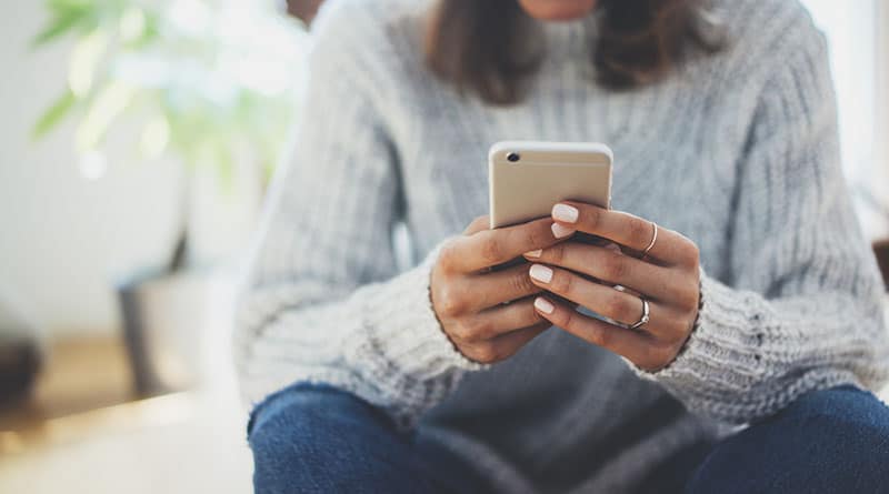 Eine Frau in einem Pullover schreibt eine SMS