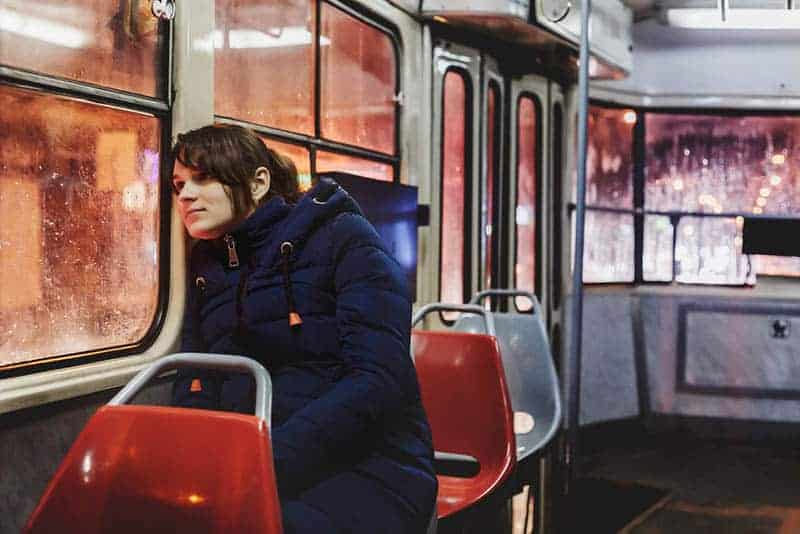 Eine Frau in einer Straßenbahn sitzt und schaut aus dem Fenster