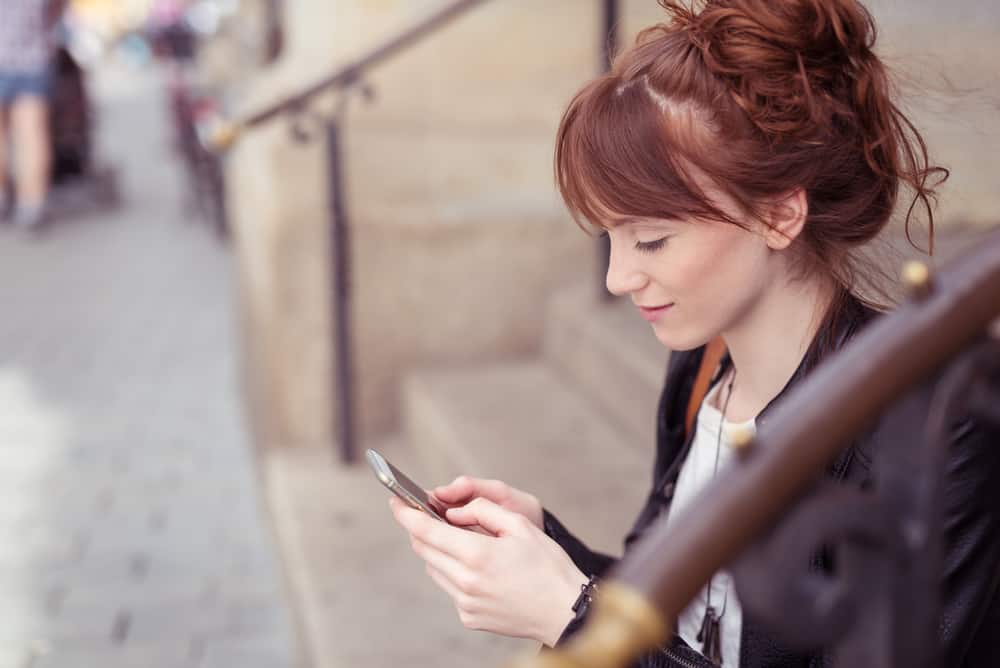 Eine schöne Frau sitzt auf der Treppe und benutzt ein Smartphone