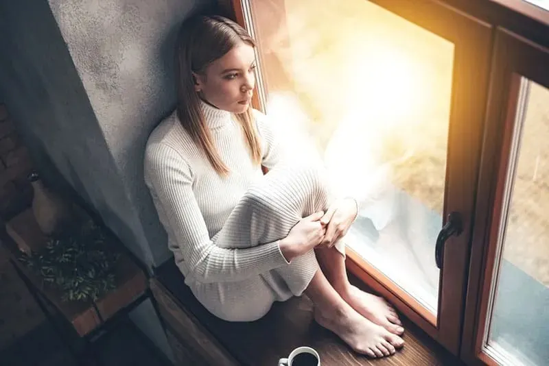 traurige Frau sitzt am Fenster