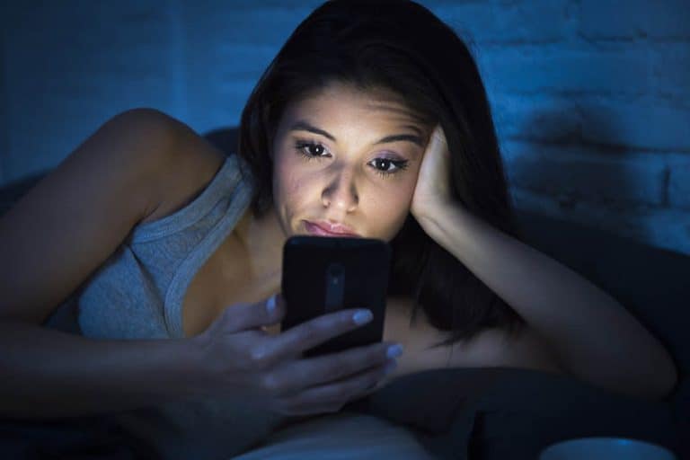 ein Mädchen, das mürrisch auf ihr Handy schaut