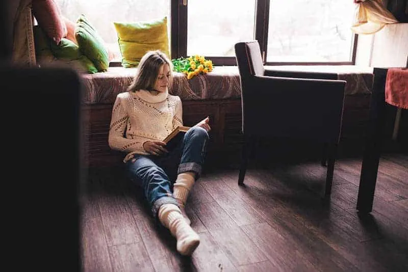 junge Frau liest ein Buch auf dem Boden