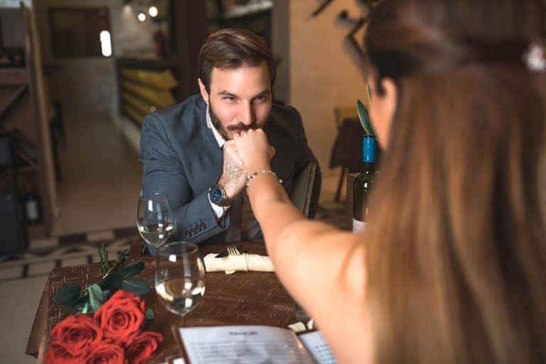 Ein Mann küsst einem Mädchen bei einem romantischen Abendessen die Hand