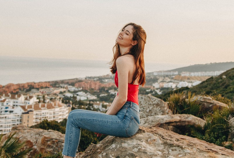 Ein glückliches Mädchen sitzt auf einem großen Felsen