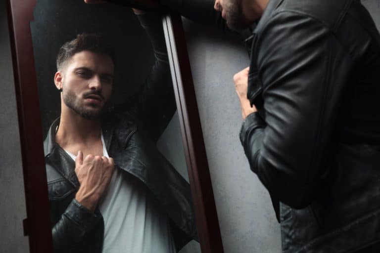 Ein narzisstischer Mann in einem schwarzen Hemd schaut in den Spiegel