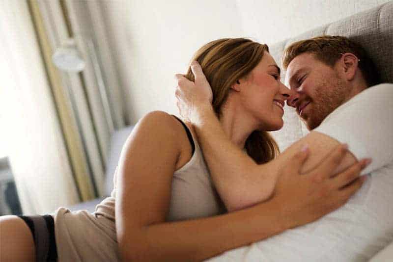 Mann küsst Frau im Bett