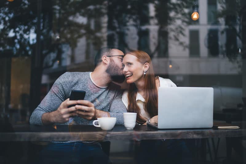 Mann küsst Frau im Café