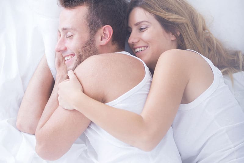 lächelndes Paar im Bett liegen