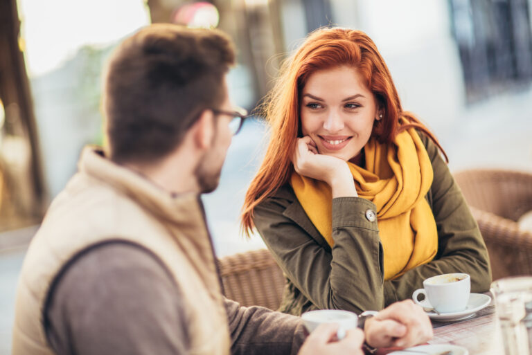 lächelnde frau, die mann beim kaffeedate ansieht