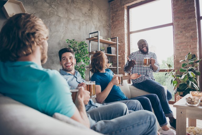 lächelnde Freunde sitzen und trinken Bier und reden